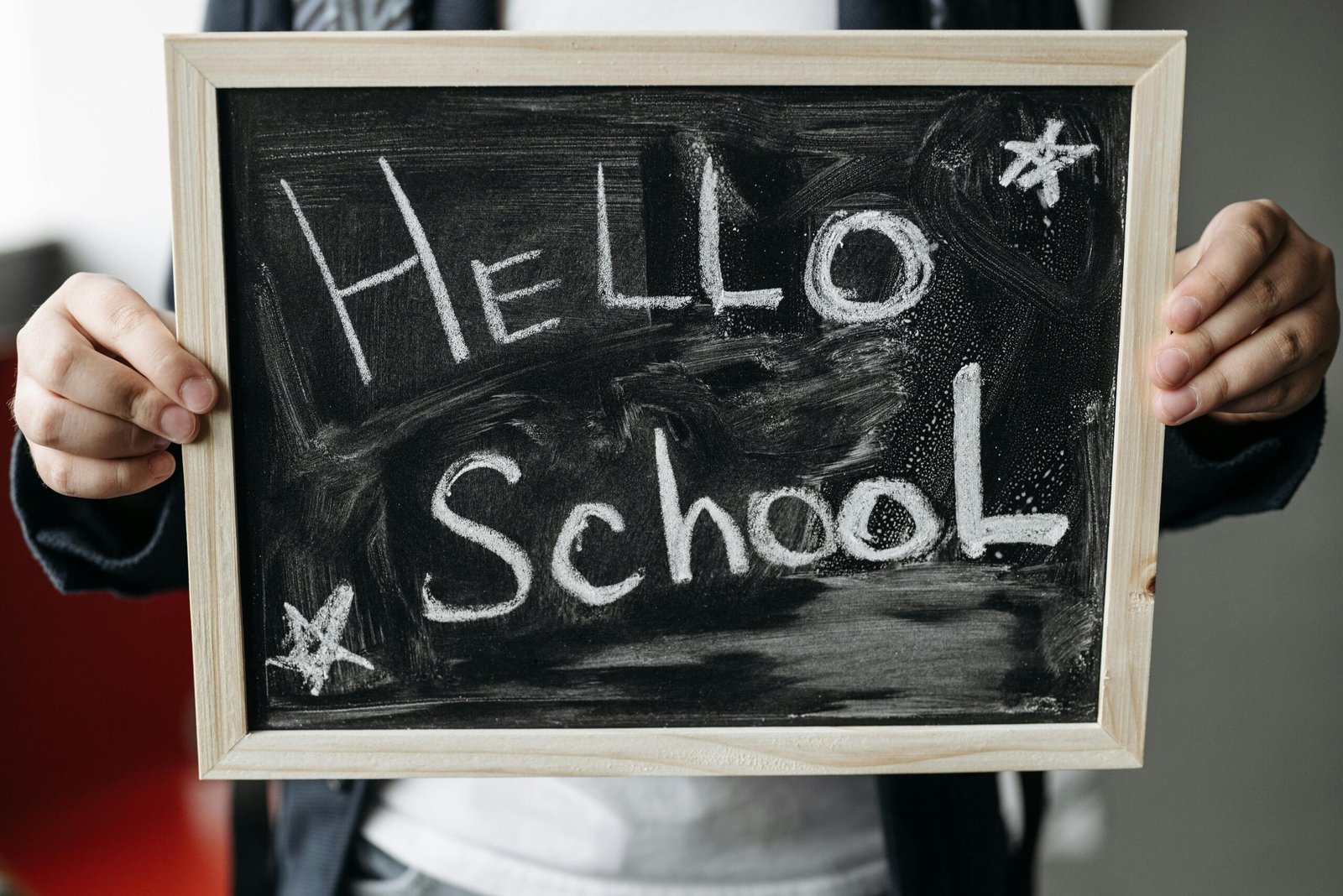 Close-up of hands holding a chalkboard with 'Hello School' message, perfect for back-to-school themes.